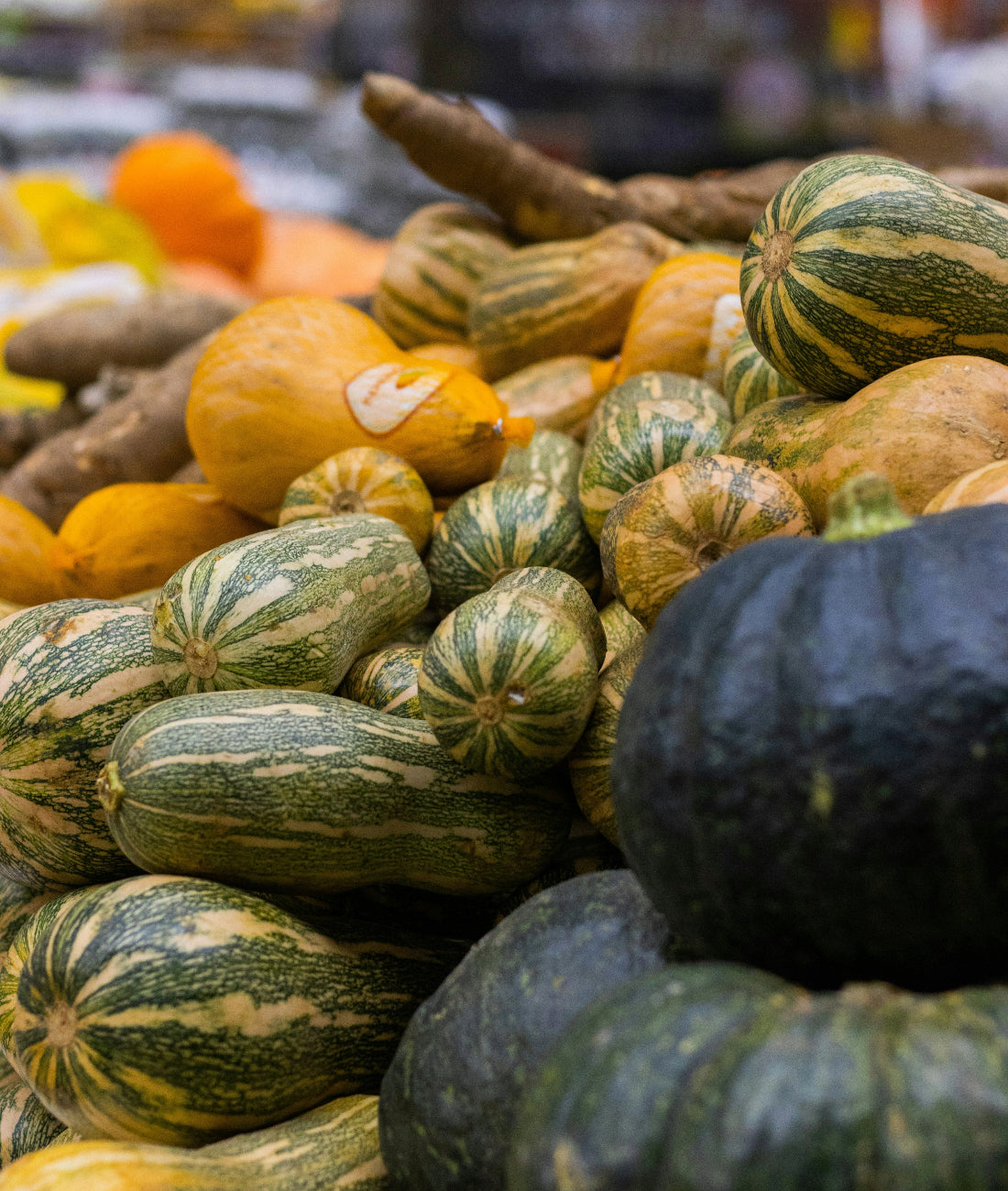 A table with several different kinds of winter squash at a farmers market